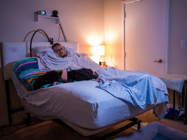 A person lies in an adjustable bed within a softly lit bedroom.
